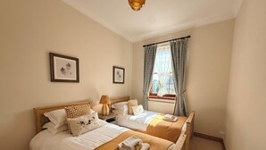 A hotel room with two beds, a window with curtains, and framed pictures on the wall. - Stylish Riverside Townhouse in Central Dumfries - Pass the Keys (Dumfries)