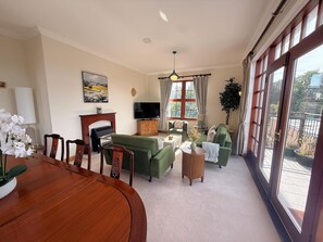 A living room with a fireplace, television, sofa, and dining table. - Stylish Riverside Townhouse in Central Dumfries - Pass the Keys (Dumfries)