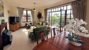 A spacious living room with a green sofa, a wooden dining table, and a television. - Stylish Riverside Townhouse in Central Dumfries - Pass the Keys (Dumfries)