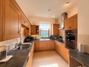 Eine moderne Küche mit Holzschränken, Edelstahlgeräten und einem Fenster, das für natürliches Licht sorgt.