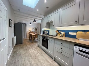 A modern kitchen with grey cabinets, a wooden countertop, and a built-in oven. - Beautiful Coastal Escape with Harbour Views/Garden - Pass the Keys (Isle of Whithorn)