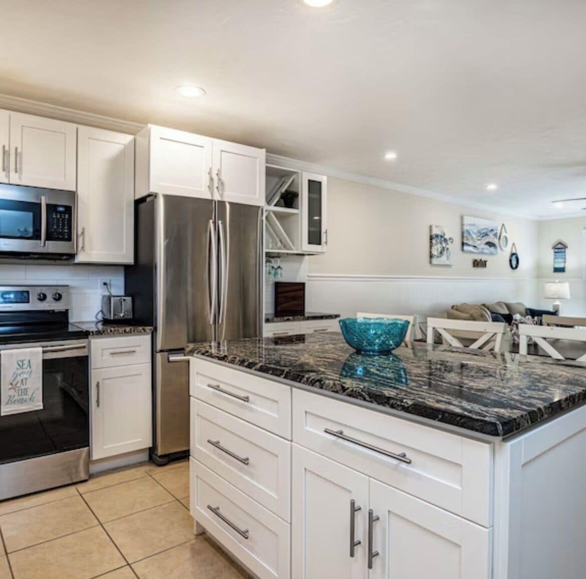 A modern kitchen with white cabinetry, stainless steel appliances, and a granite countertop.