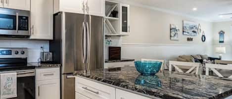 A modern kitchen with white cabinetry, stainless steel appliances, and a granite countertop.