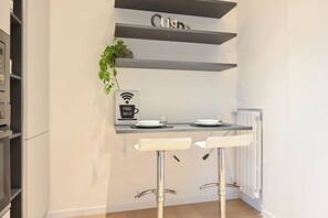Eine kleine Küchenzeile mit einer Kaffeemaschine, einer Pflanze und einem Schild für kostenloses WLAN.