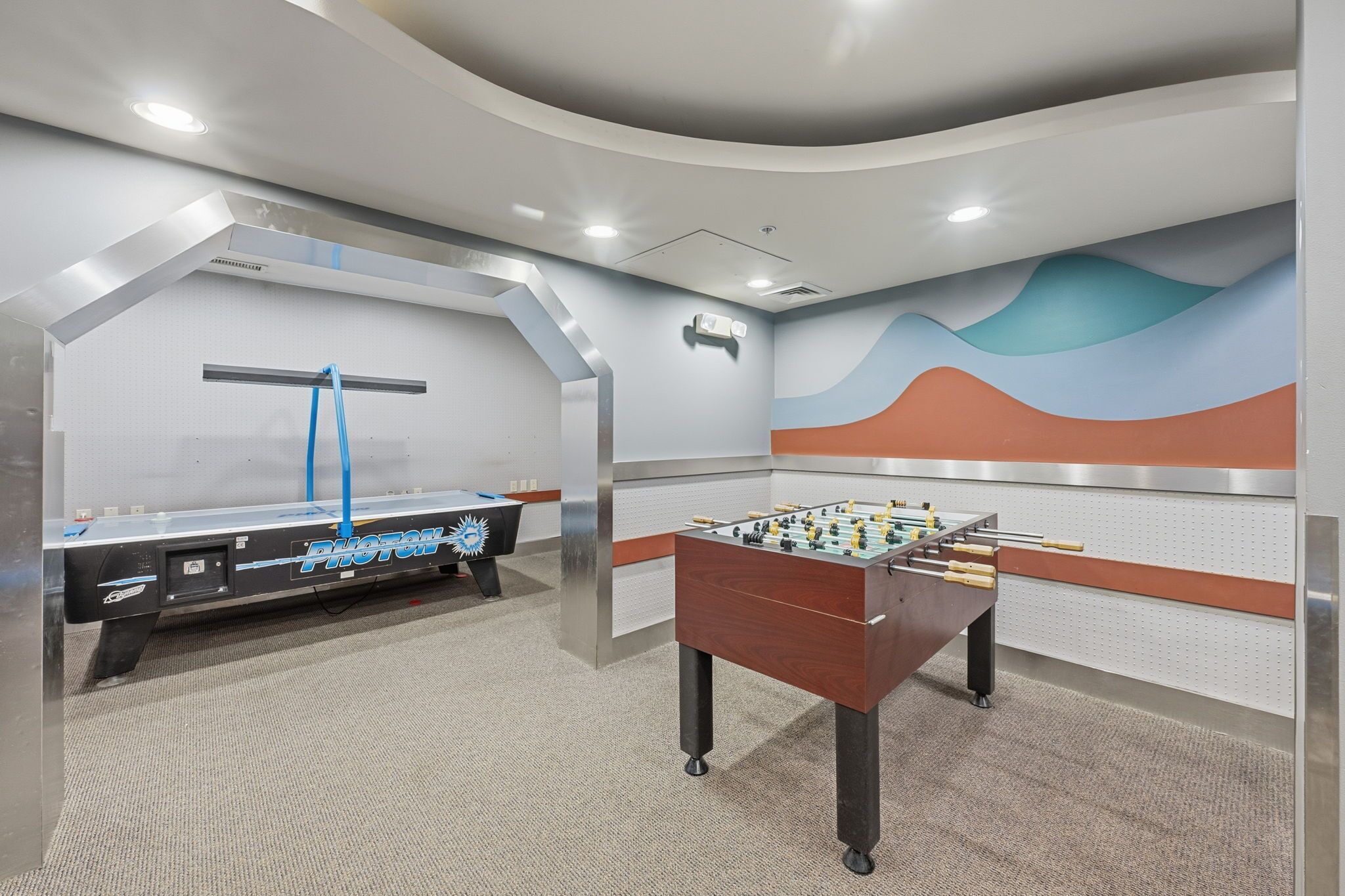 A room with a foosball table and a pool table, both with modern designs.