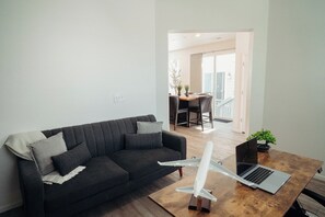 A living room with a dark sofa, a wooden coffee table, a laptop, and a model airplane. - Stylish 3BR Home + Office - Minutes from DIA & Gaylord (Aurora)