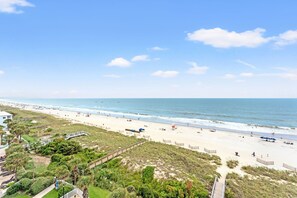 A beach with a wooden boardwalk, beach umbrellas, and a lifeguard tower. - Beautifully remodeled, oceanfront condo + Free Attraction Tickets! (North Myrtle Beach)