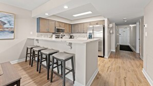 Uma cozinha moderna com ilha central, banquetas de bar e área de refeições com mesa.