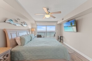 A bedroom with a bed, a ceiling fan, a TV, and a view of the ocean. - Beautifully remodeled, oceanfront condo + Free Attraction Tickets! (North Myrtle Beach)