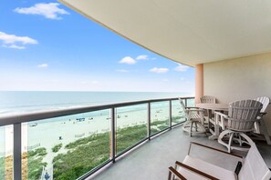 A balcony with a view of the beach, a table, and two chairs. - Beautifully remodeled, oceanfront condo + Free Attraction Tickets! (North Myrtle Beach)