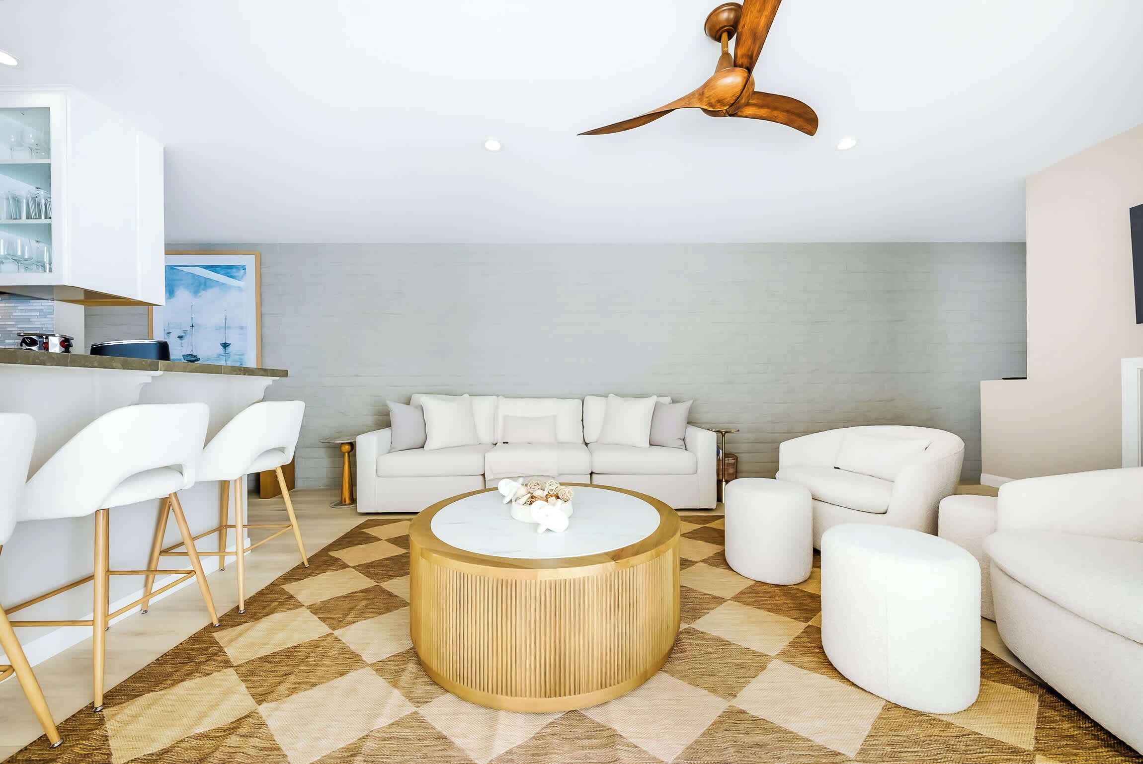 A modern living room with a white sofa, a round coffee table, and a ceiling fan.