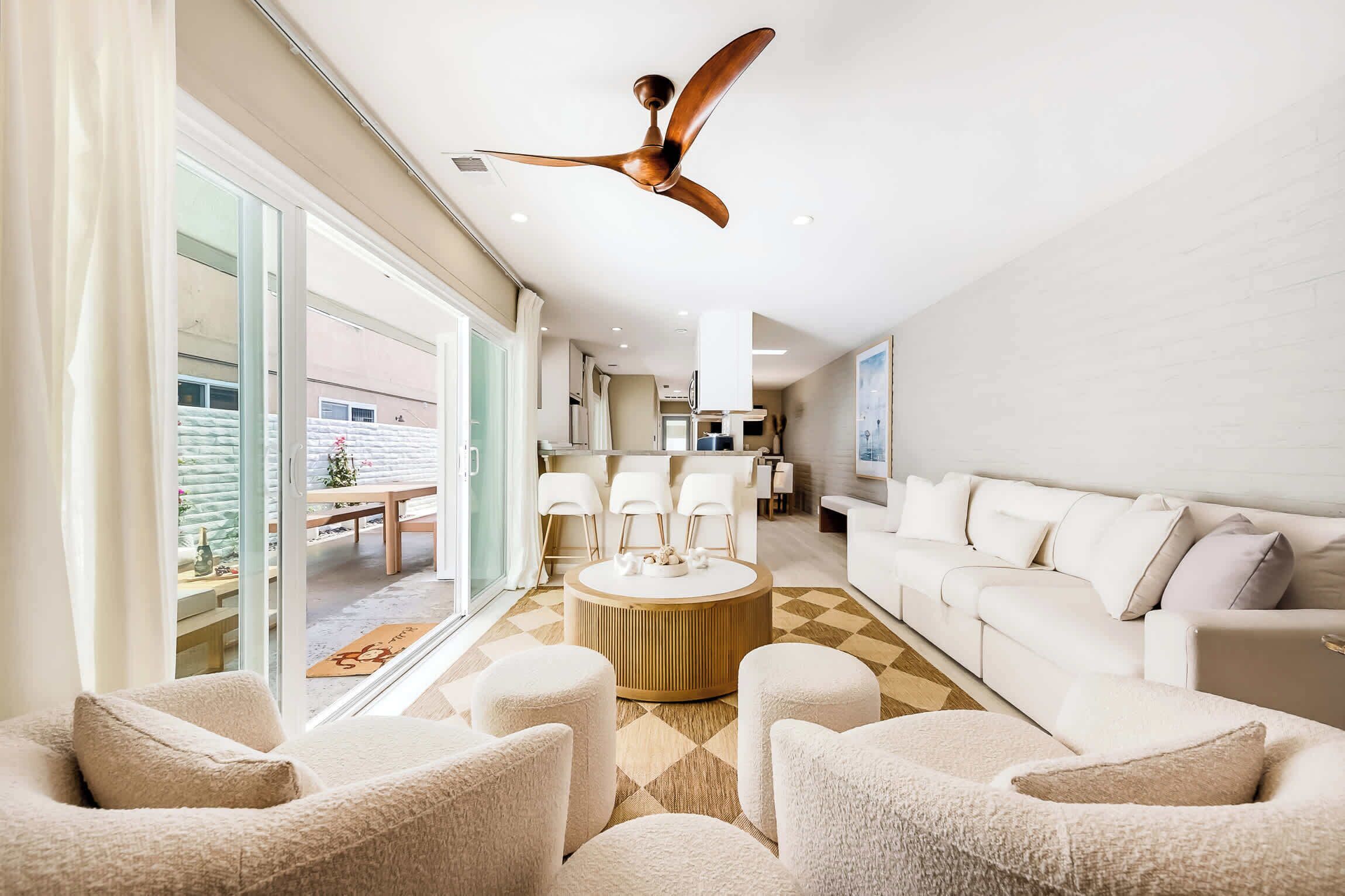 Una sala moderna con ventilador de techo, un sofá blanco y una zona de comedor con sillas.