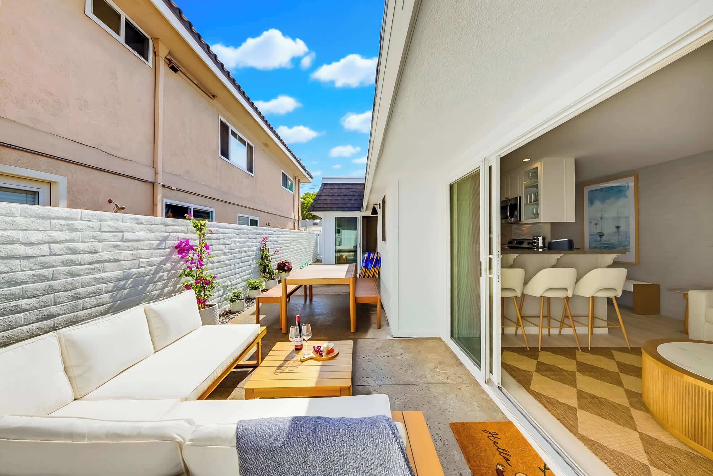 A modern apartment with a patio area, a dining table, and a kitchen visible through the sliding glass door.