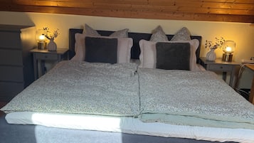 Un dormitorio con una cama grande, dos mesitas de noche con lámparas, techo de madera y alfombra gris.