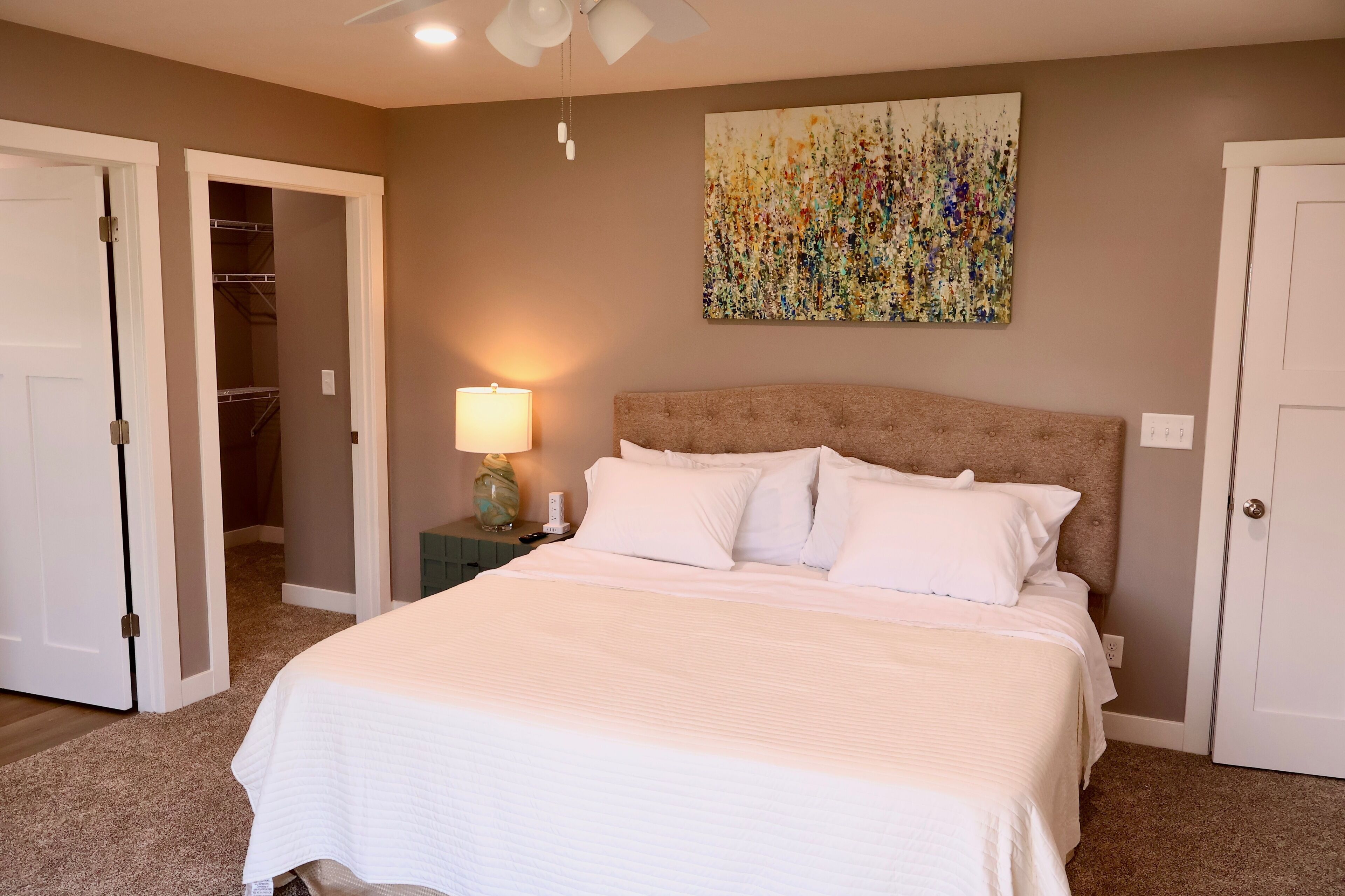 A bedroom with a bed, a nightstand, a lamp, and a ceiling fan.
