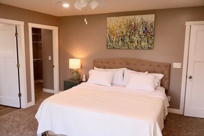 A bedroom with a bed, a nightstand, a lamp, and a ceiling fan.