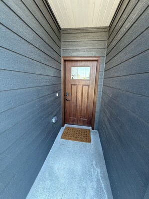 A wooden door with a number '2' sign, a doormat, and a small step leading to the entrance.