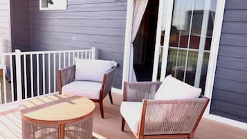Un espace extérieur abrité, aménagé avec des meubles en osier et une petite table ronde.