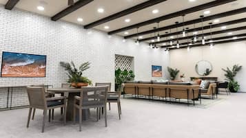 A modern dining area with a brick wall, ceiling fan, pendant lighting, and a large painting.