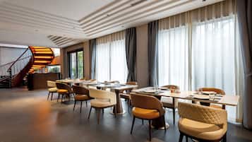 A modern dining area with a staircase, large windows, and a view of the outdoors.