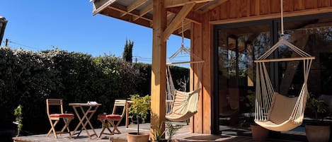 Terraza de madera con piscina, mobiliario exterior y sillas colgantes.