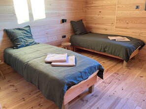 A cabin with two wooden beds, each with a green bedspread and pillows, and a small wooden stool between them. - Stunning 200 m² air-conditioned villa with a heated pool (Gujan-Mestras)