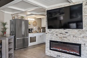 Una cocina moderna con televisión integrada, chimenea de piedra y refrigerador de acero inoxidable.