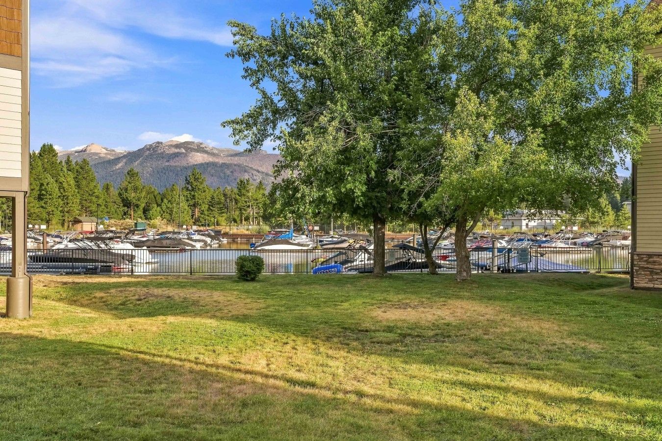 A marina with boats docked, surrounded by trees and mountains in the background.