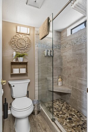 A modern bathroom with a toilet, a glass shower enclosure, and a decorative wall piece.