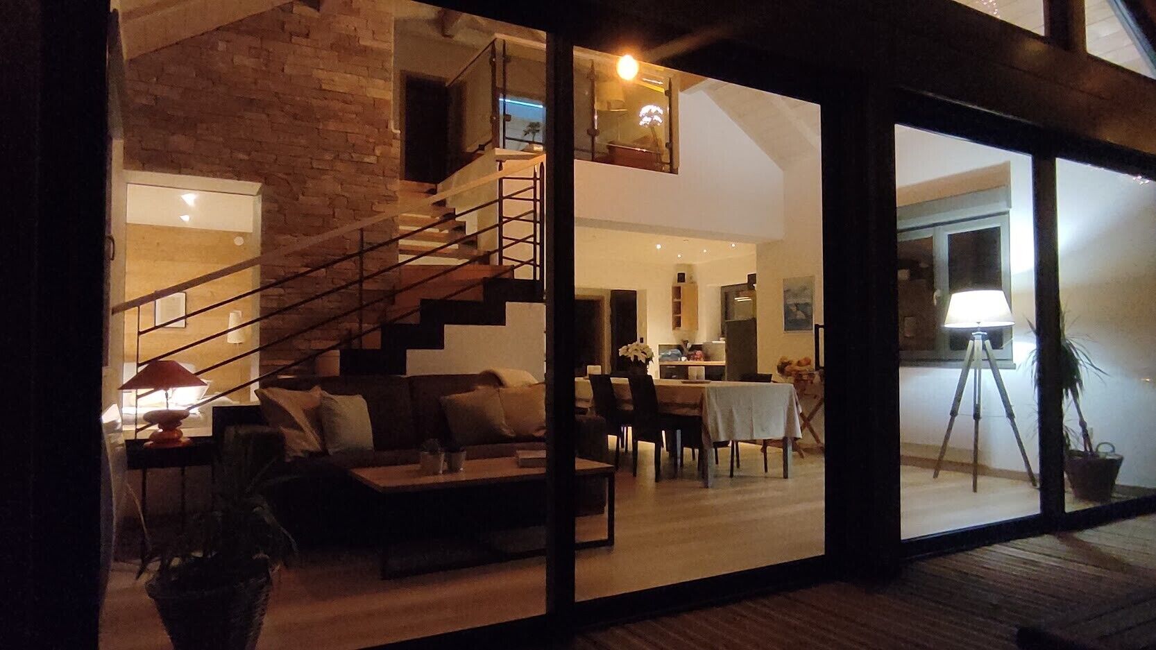 Um interior moderno com escadas, área de refeições e sala de estar com sofá e mesa de centro.