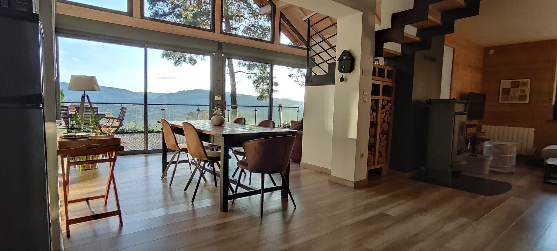 A modern dining area with a view of the outdoors, a staircase, and a fireplace.