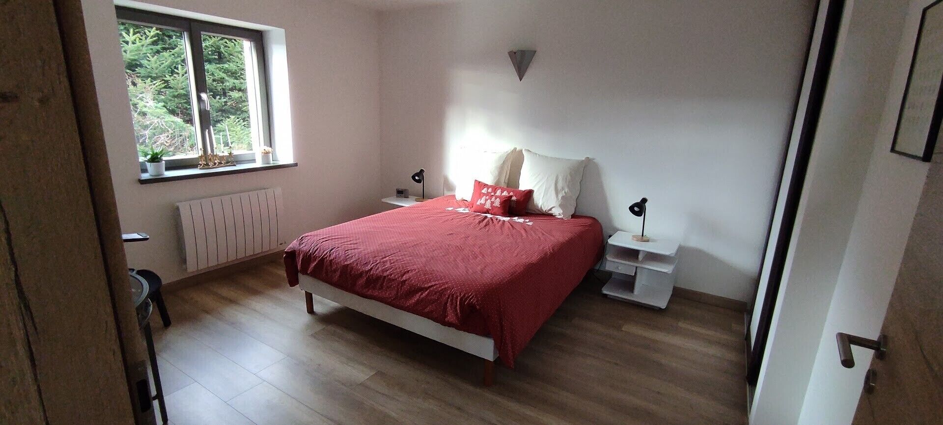 A bedroom with a bed, bedside tables, a window, and a radiator.