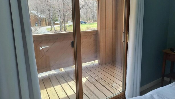 Ein Zimmer mit einer Schiebeglastür, die auf eine Holzdielen-Terrasse führt.