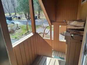 Eine Holztreppe führt zu einem Außenbereich mit Blick auf einen Wald und ein Gewässer.