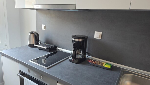 A kitchen with a coffee maker, kettle, and a tray with coffee pods. - KYANA Luxury KVA (Kavala)