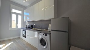 Una cocina moderna equipada con lavadora, refrigerador y cafetera.