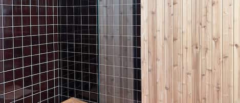 A shower area with a wooden stool, tiled walls, and a wooden panel wall.