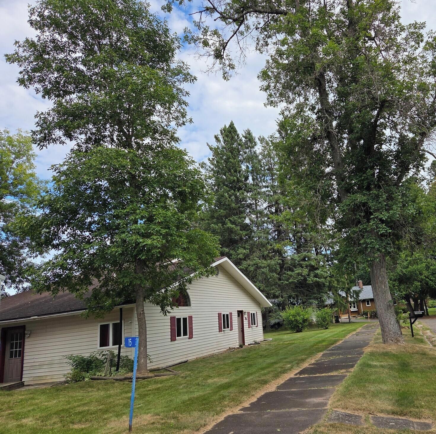 A single-story house with a front porch, surrounded by trees and a well-maintained lawn.