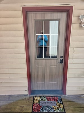 A wooden door with a red frame, a glass panel, and a welcome mat with mosaic tiles. - Spacious home with extra lofts, near Duluth with Jay Cooke State Park steps away (Carlton)