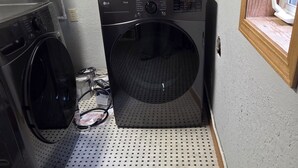 Ett tvättrum med två tvättmaskiner, en torktumlare och en kontrollpanel på väggen.