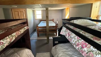 Un dormitorio con literas, techo de madera y una ventana.