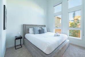 Ein Schlafzimmer mit einem Bett, einem Nachttisch und großen Fenstern.