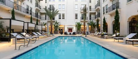 A pool area with lounge chairs and a fire feature in the center.