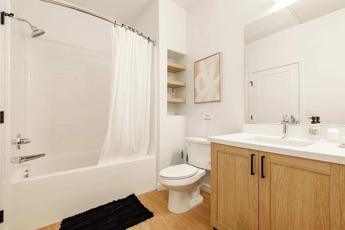 A modern bathroom with a bathtub, toilet, and vanity.