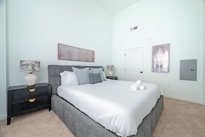 A bedroom with a bed, nightstands, and wall art.