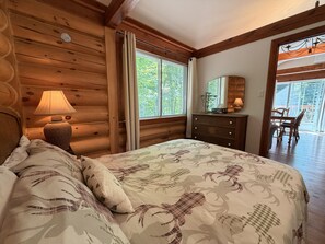 Une chambre dans une cabane en bois, avec un lit, une commode et une fenêtre avec des rideaux.