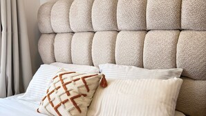 A bed with a tufted headboard and two pillows, one with a geometric pattern. - Cozy studio bed & breakfast in quaint Nairobi with 
swimming pool (Nairobi)