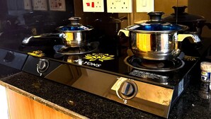 A kitchen with a black stove top, two pots, and a jar of spices. - Cozy studio bed & breakfast in quaint Nairobi with 
swimming pool (Nairobi)