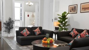 Una sala de estar moderna con un sofá negro, una mesa de centro con fruta y baldosas de suelo estampadas.