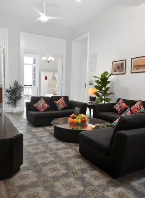 A modern living room with a black sofa set, a coffee table with fruit, and patterned floor tiles. - Stunning specious luxury apartment high ceiling (Cairo Governorate)